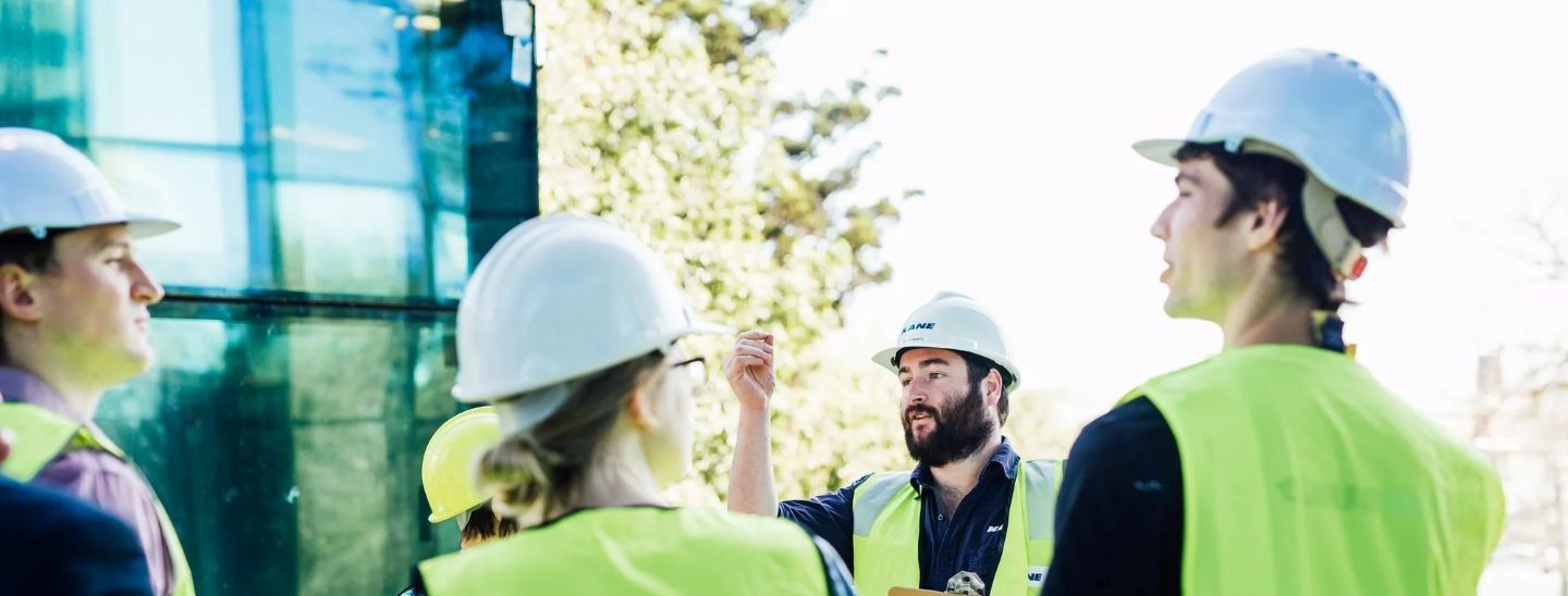 Students wearing hard hats and high-visibility safety vests participating in an engineering site visit.