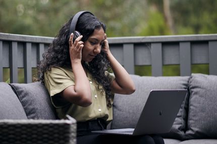 Stemp young woman relaxes outdoors on laptop with headphones