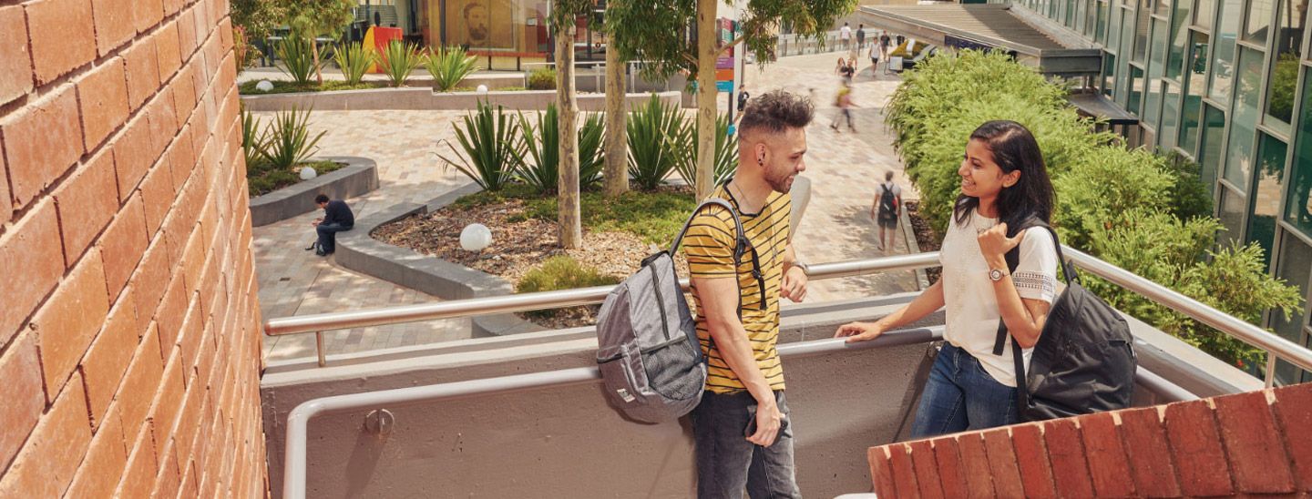 Campus couple standing on staircase outside red brick wall building