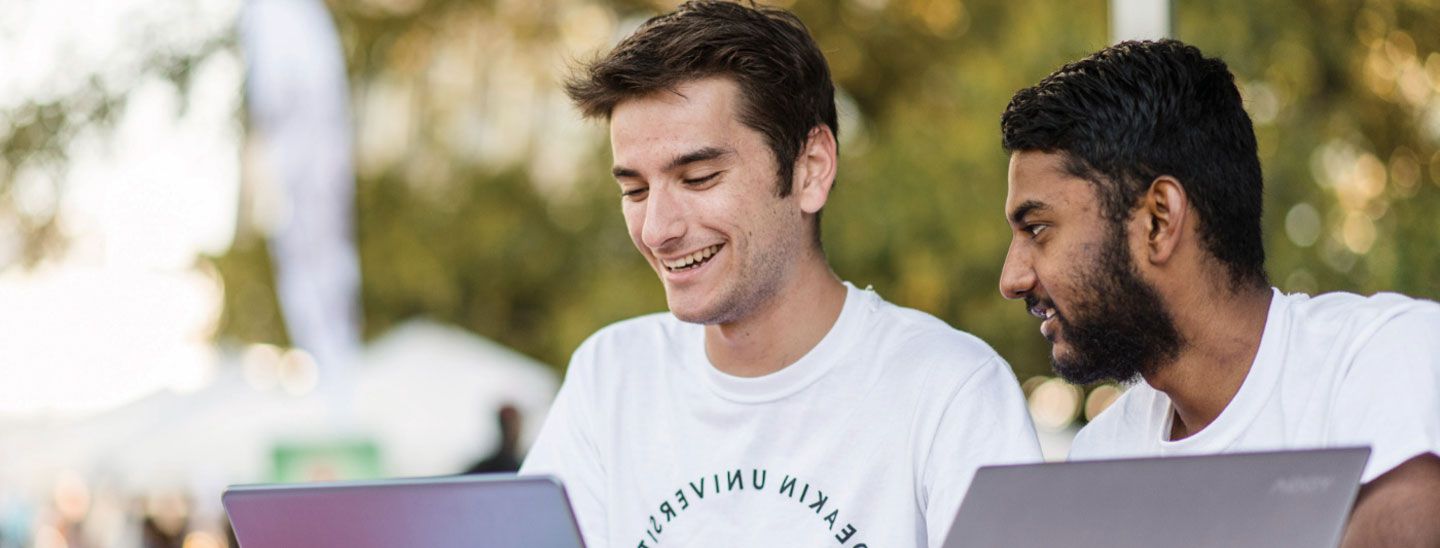 Campus couple working on laptops outside