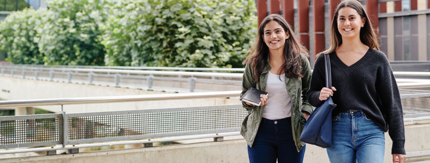 Campus female couple on footbridge