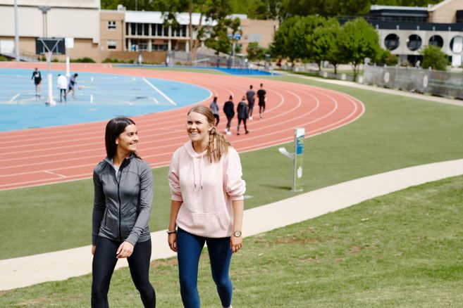 Campus female couple walking near running track