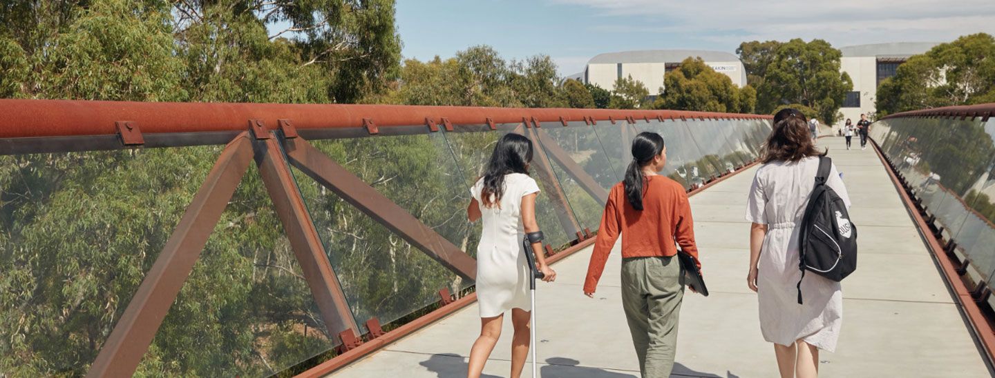 Campus female group crossing footbridge