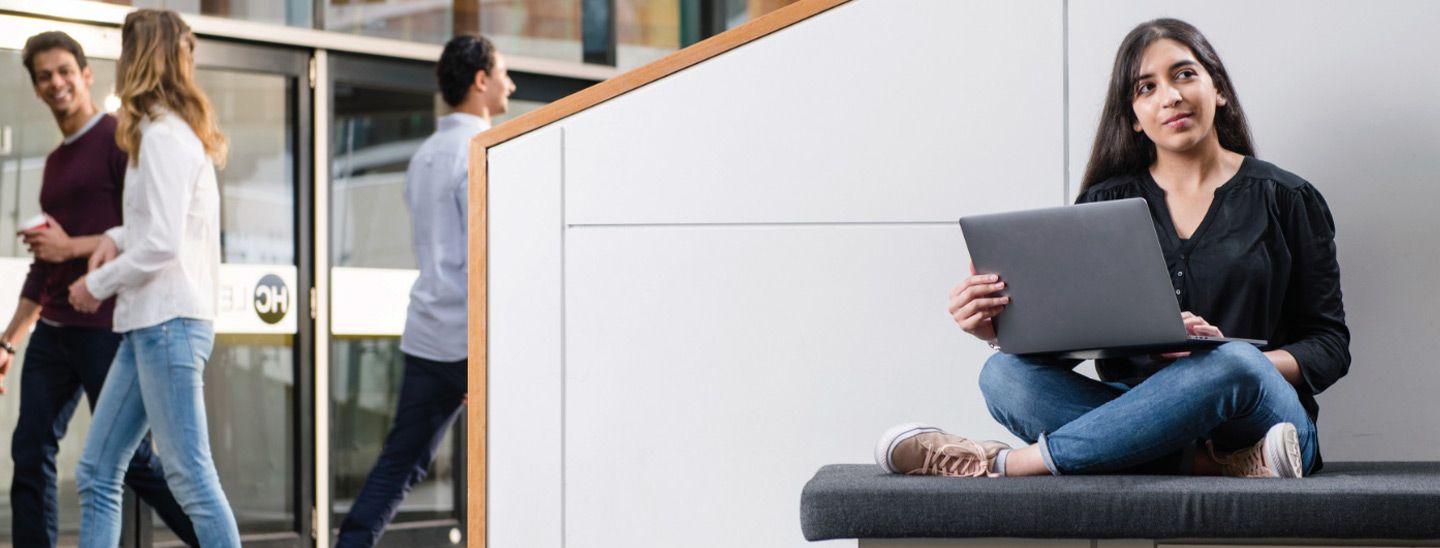 Campus female sitting on bench with laptop