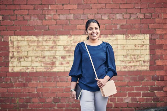 Campus female standing infront brick wall