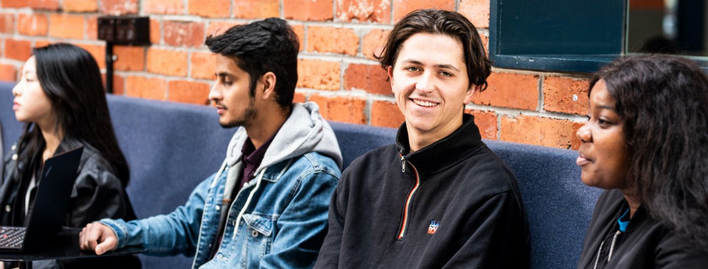 Campus group sitting in-front of red brick wall