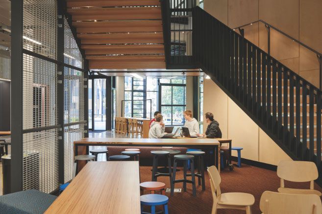 Campus group studying at table under stairs