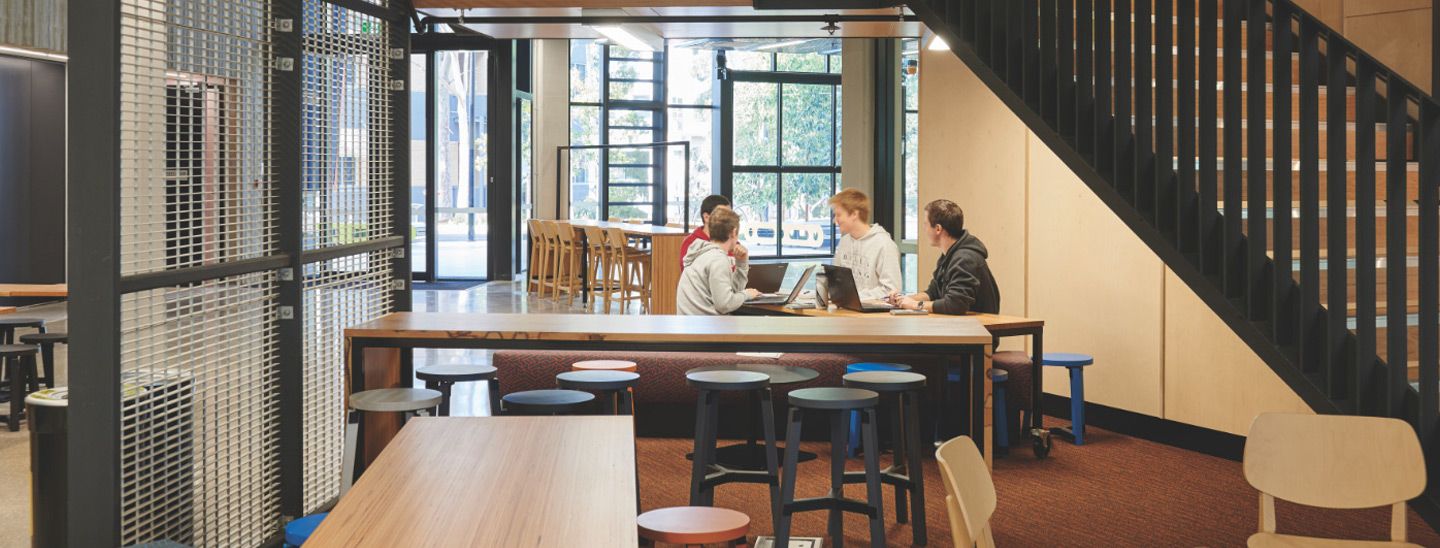 Campus group studying at table under stairs