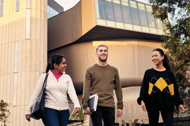 Campus group walking in front of concrete building