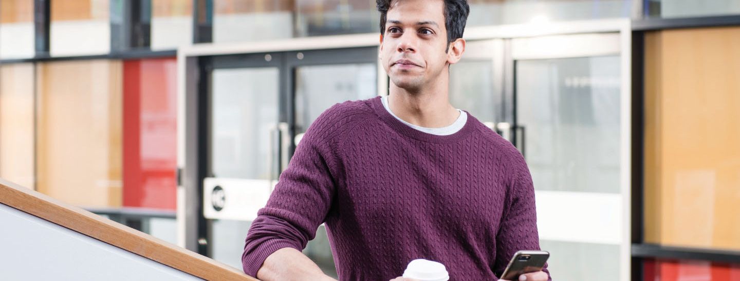 Male holding phone and coffee cup