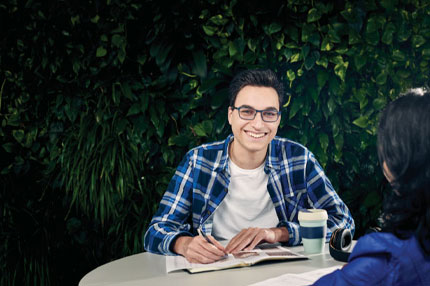 Male writing in book smiling