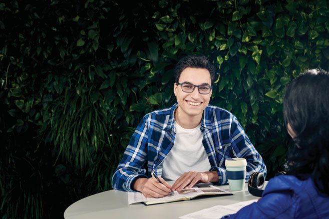 Male writing in book smiling