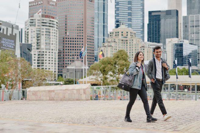 Off campus couple walking over bridge in city